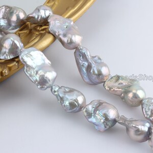 May include: A strand of baroque freshwater pearls in shades of grey and white. The pearls are irregular in shape and have a high lustre.