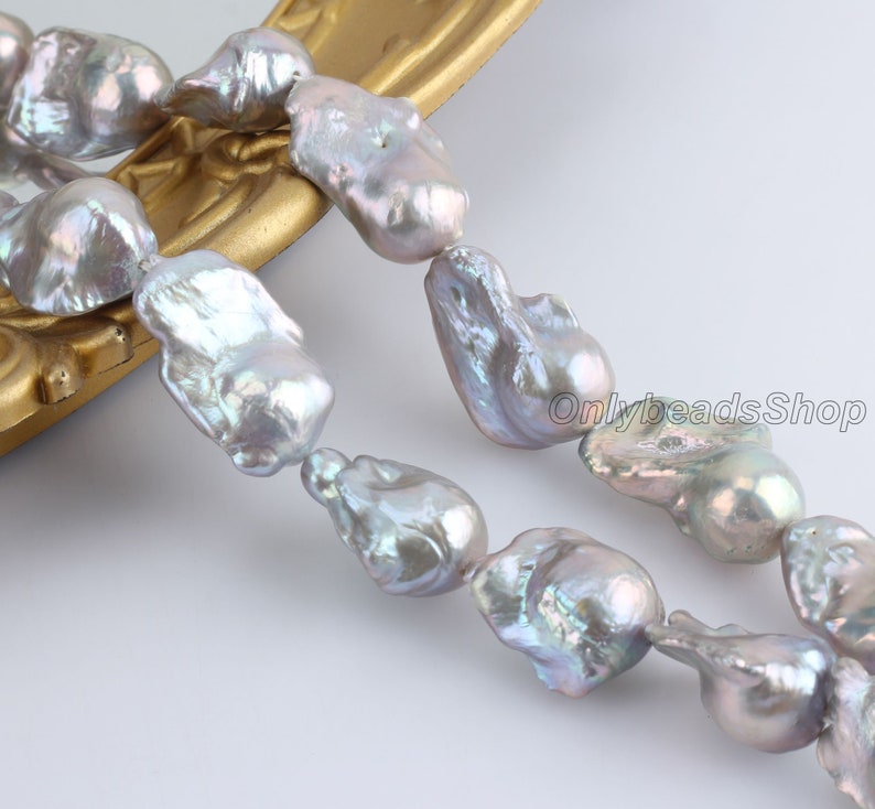 May include: A strand of baroque freshwater pearls in shades of grey and white. The pearls are irregular in shape and have a high lustre.