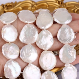 Puede incluir: Una hebra de cuentas de perlas de agua dulce blancas. Las perlas son grandes y redondas, con una superficie lisa y pulida. Las cuentas están enhebradas en un cordón blanco.