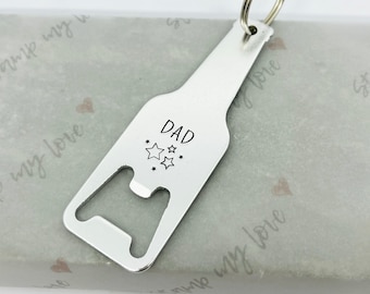 May include: Silver bottle opener keychain with a bottle shape and a ring. The opener has the word "DAD" engraved on it with stars around the word.