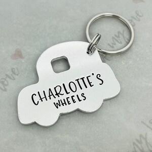 May include: Silver car-shaped keychain with the text "CHARLOTTE'S WHEELS" engraved on it.