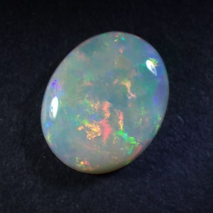 May include: A white opal gemstone with iridescent flashes of green, blue, and pink.