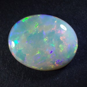 May include: A white opal gemstone with a light blue body colour and iridescent flashes of green, purple, and pink.