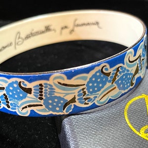 Peut inclure: Un bracelet jonc en émail bleu et blanc avec un motif floral. L'intérieur du bracelet est blanc et porte l'inscription "Franco Bassetti, per l'amore".