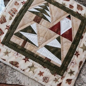 May include: A festive quilted placemat with a Christmas theme. The central design features stylized Christmas trees and a Santa Claus figure. The border is decorated with stars, hearts, and gift box patterns in green, red, and beige.
