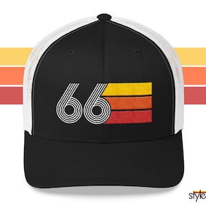 May include: Black trucker cap with a white mesh back and a curved peak. The front displays the number "66" in white, with a retro design. Below the number is a horizontal rectangle with orange, yellow, and red stripes.