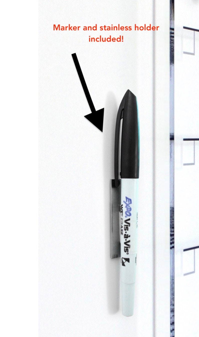 Op de afbeelding: Een wit whiteboard met een zwarte marker die aan een roestvrijstalen houder is bevestigd. De marker is ge&euml;tiketteerd "Expo Vis-&agrave;-Vis" en heeft een zwarte dop. De tekst "Marker en roestvrijstalen houder inbegrepen!" staat in het rood boven de marker.
