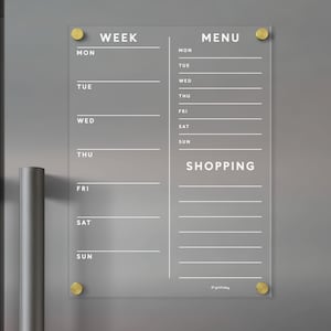 Może przedstawiać: Przezroczysty, akrylowy planer tygodniowy z złotymi pinezkami. Planer zawiera sekcje "Tydzień", "Menu" i "Zakupy" z miejscem na wpisanie każdego dnia tygodnia.