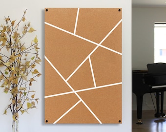May include: A corkboard with a geometric design of white lines on a brown background. The corkboard is mounted on a white wall.