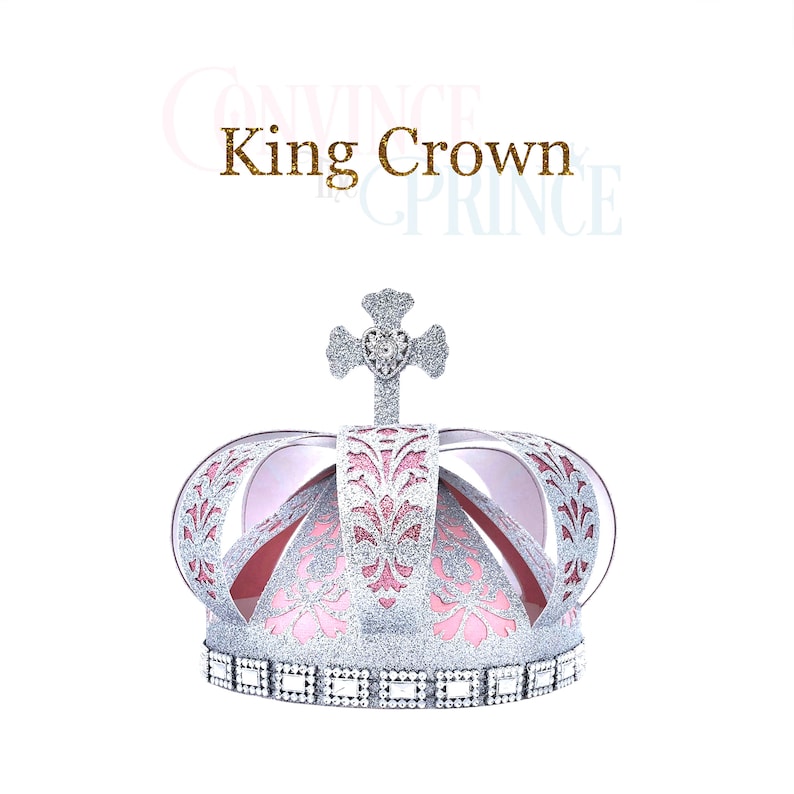 May include: A silver and pink glitter crown with a heart-shaped jewel on top. The crown has a cross on top and a band of rhinestones around the bottom. The text "King Crown" is written in gold glitter above the crown.