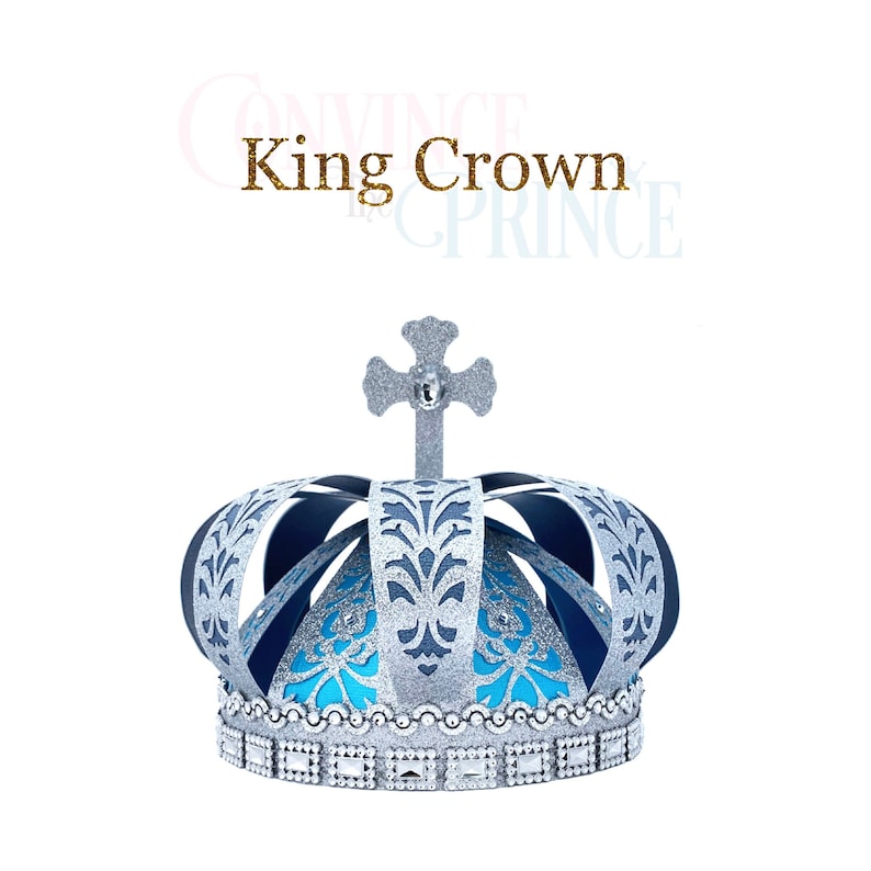 May include: A silver and blue king crown with a cross on top. The crown has a blue and silver patterned design and a silver band with rhinestones.