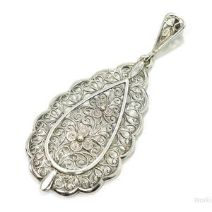 May include: A silver filigree pendant in the shape of a teardrop with intricate floral designs.