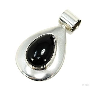 May include: A silver-tone pendant featuring a polished black stone in a teardrop shape. The pendant has a smooth, reflective surface and a loop for a chain. The jewellery item is shown against a white background.
