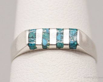 May include: A silver band ring with five turquoise inlay stripes.