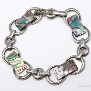 May include: A silver bracelet with four iridescent abalone shell rectangular inlays. The bracelet has a lobster claw clasp.