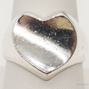 May include: A silver heart-shaped ring with a smooth, rounded surface.