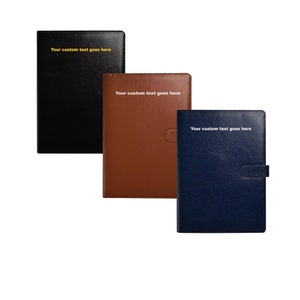 May include: Three leather journals in black, brown, and navy blue. Each journal features the text "Your custom text goes here" in gold or white. The brown journal has a magnetic clasp.