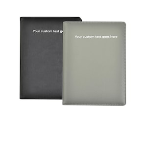 May include: Two personalised leather journals, one black and one grey, with the text "Your custom text goes here" printed in white.