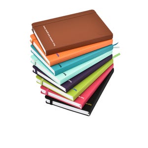May include: A pile of notebooks in a range of colours: brown, orange, turquoise, purple, green, pink, and black. Each notebook has a matching ribbon bookmark and the text "Your custom text goes here" printed on the cover.