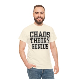 May include: A cream-coloured short-sleeve t-shirt with a speckled texture. The front features the text "CHAOS THEORY GENIUS" printed in a bold, black, block-style font with a white outline, arranged in three stacked lines across the chest.