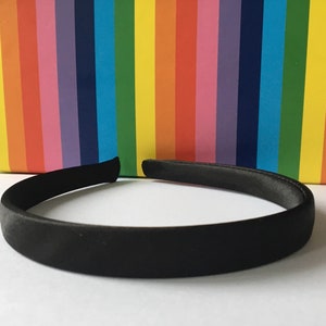 Könnte beinhalten: Ein schwarzes Satin-Haarband. Das Haarband ist ein schlichtes, klassisches Design, das zu jedem Outfit passt.