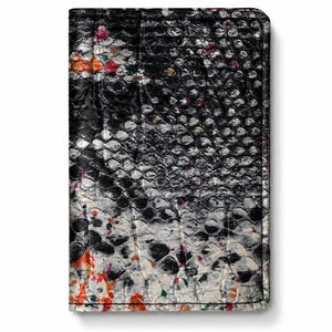 Peut inclure: Un portefeuille rectangulaire avec un motif peau de serpent. Le portefeuille présente une palette de couleurs noire, blanche et grise avec de petites touches d'orange et de rose. Les bords sont cousus avec du fil noir.