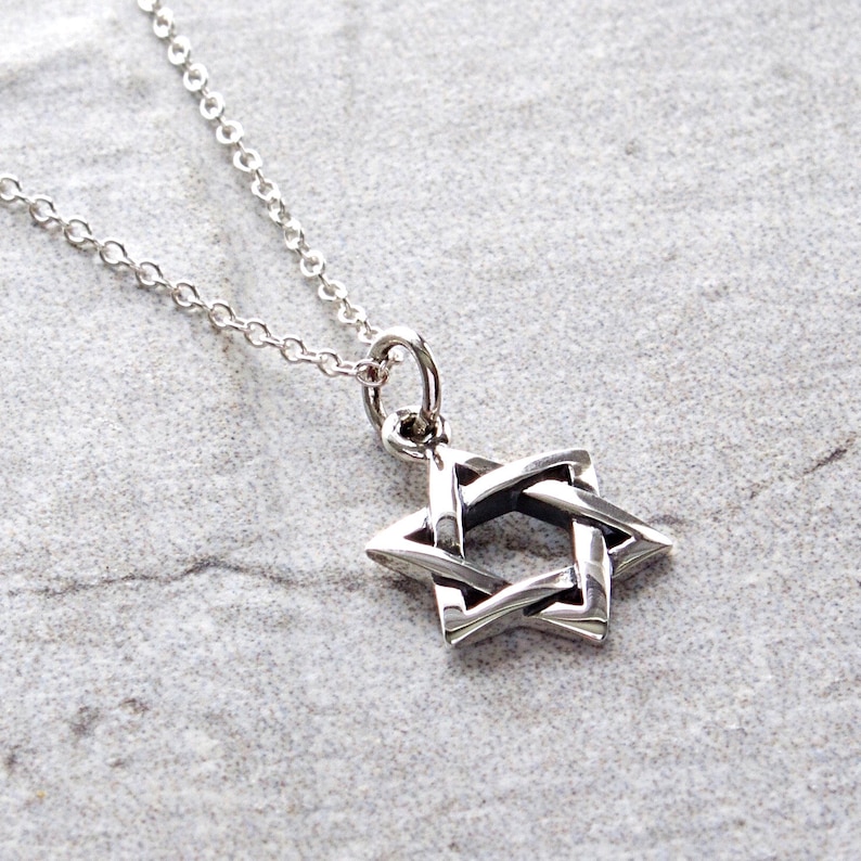 May include: A silver chain necklace with a silver Star of David pendant. The pendant is a detailed, intricate design.