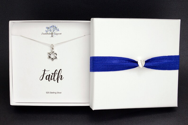 May include: A silver necklace with a Star of David pendant in a white box with a blue ribbon. The box has the word "Faith" written on it and the text "925 Sterling Silver".