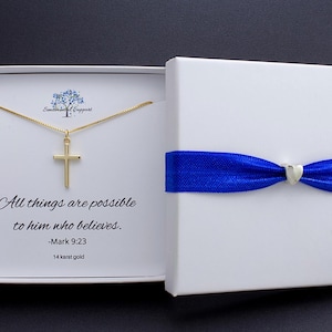 May include: A gold cross pendant necklace inside a white gift box with a blue ribbon. The box is open, revealing the necklace and text that reads "All things are possible to him who believes. -Mark 9:23". The necklace is 14 karat gold.