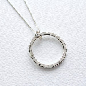 May include: A silver necklace with a hammered circle pendant.