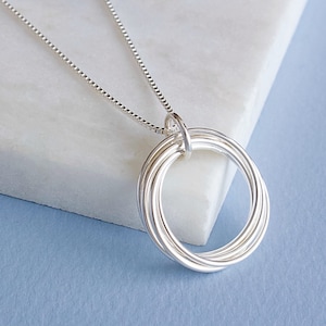 May include: Silver necklace with a pendant made of five interlocking circles.