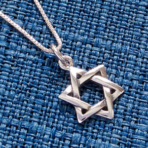 May include: A silver Star of David pendant necklace on a silver chain. The pendant is a simple, geometric design with a six-pointed star.