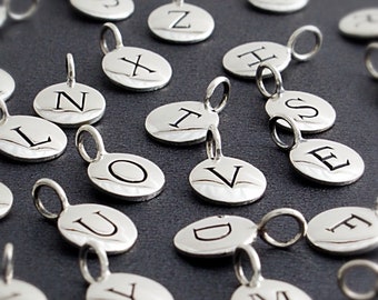 Peut inclure: Un ensemble de breloques en argent avec différentes lettres de l'alphabet gravées dessus. Chaque breloque a une petite boucle en haut pour l'attacher à une chaîne ou un bracelet.