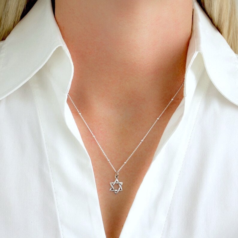 May include: A silver chain necklace with a small silver Star of David pendant.