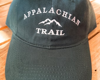 May include: A dark green baseball cap with white embroidery that reads "Appalachian Trail" and features a stylized mountain range graphic.