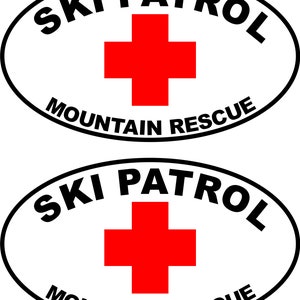 May include: Two white oval stickers with black outlines. The stickers say "SKI PATROL MOUNTAIN RESCUE" in black text. A red cross is in the center of each sticker.