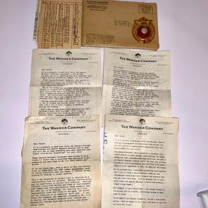 May include: A collection of vintage Captain Midnight memorabilia, including a chart, an envelope with a badge, and several letters from The Wander Company. The items are on a light-colored surface, showcasing a nostalgic theme.