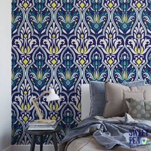 May include: A navy blue wallpaper with a repeating floral pattern in white, yellow, and teal. The wallpaper is installed on a wall behind a bed with pillows and a blanket. A small table with a lamp and magazines is in front of the wall.