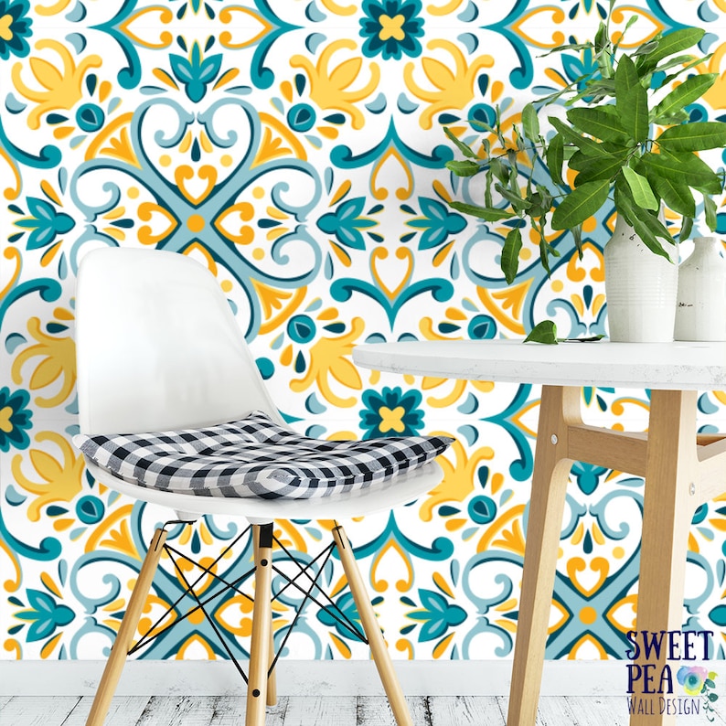May include: A white chair with a black and white checkered cushion sits in front of a wall covered in teal and yellow patterned wallpaper. The wallpaper features a repeating geometric design with floral accents. A white table with a wooden base sits in the foreground.