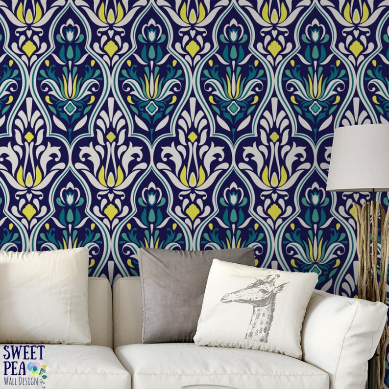May include: A navy blue and white patterned wallpaper with teal and yellow accents. The design features a repeating floral motif. The wallpaper is installed on a wall behind a white sofa with pillows. The Sweet Pea Wall Design logo is visible.