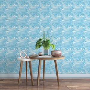 Pu&ograve; includere: Due tavoli in legno con una carta da parati a onde blu e bianche sullo sfondo. I tavoli sono decorati con un vaso di piante verdi, una ciotola e un oggetto decorativo.