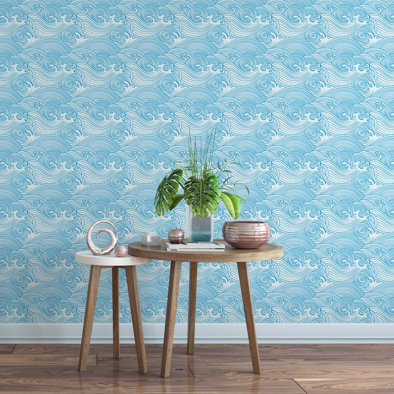 Pu&ograve; includere: Due tavoli in legno con una carta da parati a onde blu e bianche sullo sfondo. I tavoli sono decorati con un vaso di piante verdi, una ciotola e un oggetto decorativo.