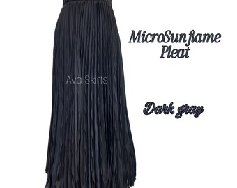 May include: Dark gray pleated skirt with the text "MicroSunflame Pleat" and "Ava Skirts". The skirt is a dark gray color and has a pleated design. The words "Dark gray" are also visible.