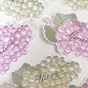 Hand painted and printed watercolour grape place cards with walnut ink personalised calligraphy guest names. Choose from a green bunch of grapes or a purple bunch of grapes. Or have a mix of both colours. Perfect for a Mediterranean wedding, winery event or a party on a vineyard. Classic grape place card are great for a long Italian or Greek lunch under the grapevines.