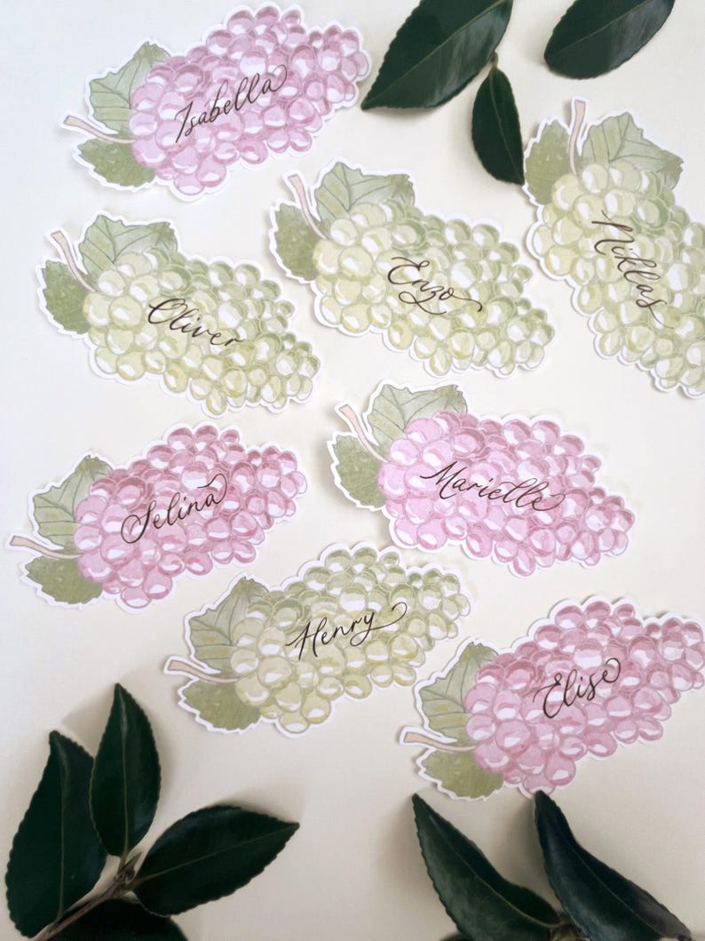 Hand painted and printed watercolour grape place cards with walnut ink personalised calligraphy guest names. Choose from a green bunch of grapes or a purple bunch of grapes. Or have a mix of both colours. Perfect for a Mediterranean wedding, winery event or a party on a vineyard. Classic grape place card are great for a long Italian or Greek lunch under the grapevines.
