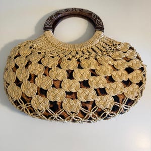 Op de afbeelding: Een beige geweven handtas met een bruin luipaardprint interieur. De tas heeft een ronde houten handgreep en een geweven ontwerp. Een stijlvol accessoire voor het dragen van essentials.
