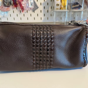 May include: A dark brown leather handbag with a woven center panel. The bag has a rectangular shape with a zipper closure and a silver chain strap. The leather has a textured appearance.