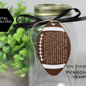 May include: A brown football-shaped tag with white stitching and text that reads "On this grass, you've literally left it all - blood, sweat, and tears. You've made friendships that will always be a part of you. You've fought side by side with guys who can relate with how bad you want to win. This grass holds your laughter, as tightly as it holds your frustration. Life goes on off of the field, but nothing can compare to the feeling you get while standing on it. Each time you look at this piece of grass, know in your heart what it stands for and remember those years and all of the memories it holds. PLAYER NAME #"  The tag is tied to a clear glass jar with a black ribbon.