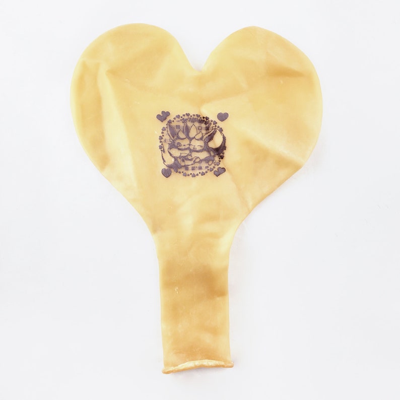 May include: A yellow heart-shaped balloon with a black and white graphic of two cartoon animals inside a circle with hearts around it.