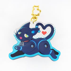 May include: A blue and black cat with a heart on its tail, printed on a clear acrylic keychain with a gold chain.